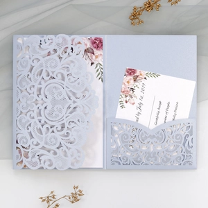 Macro view of laser-cut wedding invitation set with floral inserts and pearlescent paper