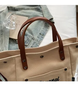 Detail of canvas tote bag with brown leather handles and vintage metal rivets