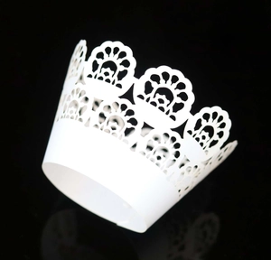 Close-up of white laser-cut lace cupcake wrappers with elegant floral hollow patterns