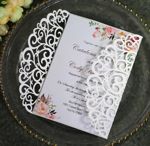 Detail of laser-cut lace wedding invitation with floral printed inner card and white shell