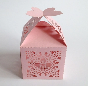 Makroaufnahme der rosa Gastgeschenkbox mit Laserschnitt, Kreuzmotiv und Schmetterling