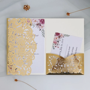 Macro detail of laser-cut gold wedding invitation with elegant floral RSVP card insert