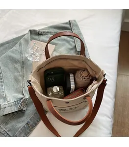 Macro view showing the large capacity of a canvas tote bag with phone, umbrella and water bottle