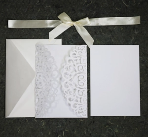 Laser cut lace wedding invitation card with intricate vine pattern and cream ribbon