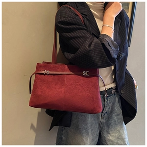Détail du cabas en daim bordeaux avec boucle métallique porté avec un blazer à rayures bleu