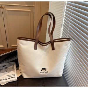 Canvas tote bag detail with brown leather trim and cute girl embroidery with text