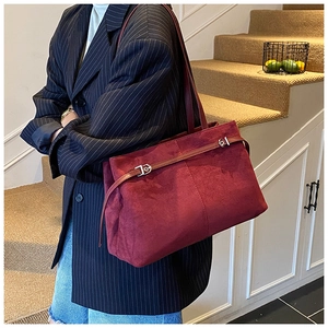 Détail d'un grand sac cabas en daim bordeaux avec boucles argentées porté par un mannequin