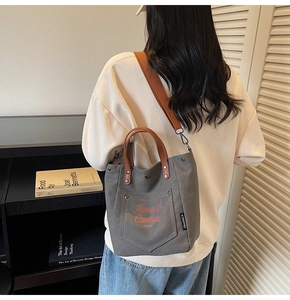 Close-up of gray canvas tote bag featuring brown leather straps and Always Canvas print