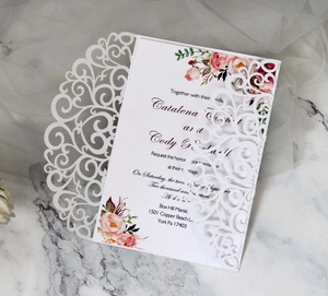 Detail of laser-cut lace wedding invitation with pink floral inner card on marble
