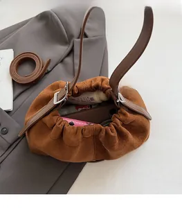 Gros plan de l'intérieur du sac seau en daim marron montrant un rangement spacieux et pratique