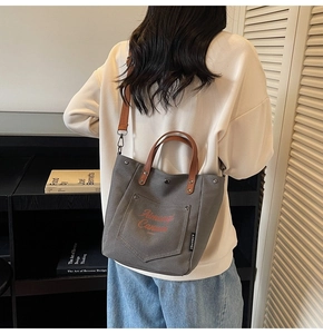 Detail view of canvas bucket bag with contrast brown strap and artistic letter print