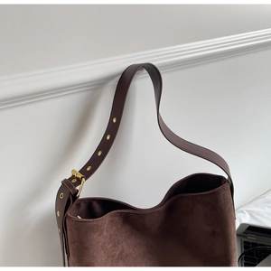 Detail of dark brown suede shoulder bag with adjustable leather strap and gold buckle