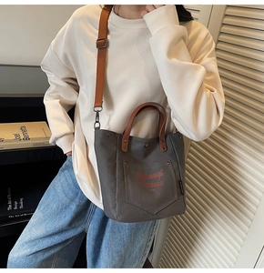 Detailed view of grey canvas tote bag featuring brown handles and adjustable shoulder strap