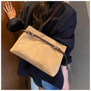 Détail de la texture d'un sac cabas en cuir mat marron et boucle sur un mannequin stylé