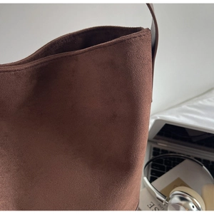 Close-up of brown suede bucket bag texture with leather strap and lifestyle accessories