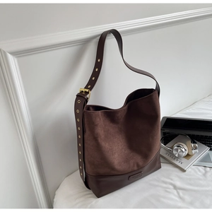 Close-up of vintage brown suede hobo bag with wide adjustable shoulder strap and metal eyelets