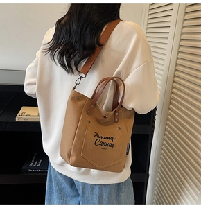 Detail of warm brown canvas tote bag with leather handle and adjustable woven shoulder strap