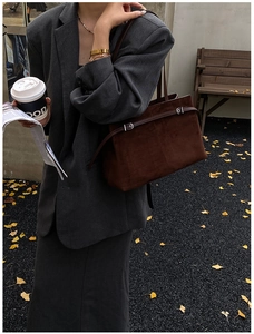 Gros plan d'un sac cabas en daim marron foncé avec boucle métallique dans un décor d'automne