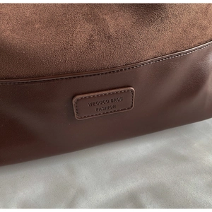 Detail of premium brown suede and smooth leather stitching with embossed designer logo patch