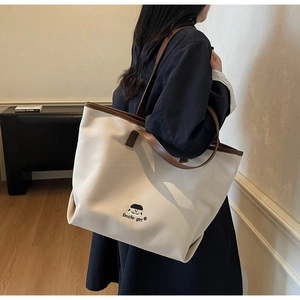 Detail of canvas tote bag featuring Docile girl cartoon character and leather handles