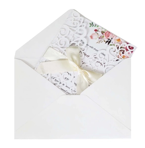 Detail of laser-cut lace wedding invitation with floral insert and silk ribbon bow