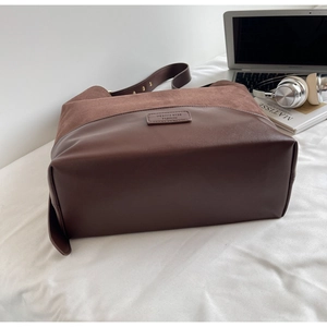 Detail of dark brown tote with suede stitching, gold eyelets and wide strap