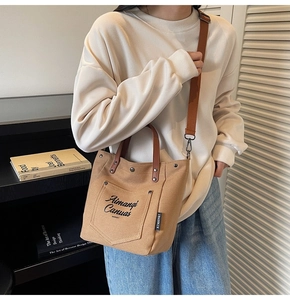 Detail showing khaki canvas tote bag with brown leather handles and brand tag