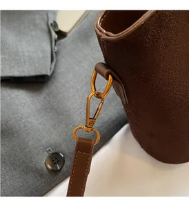 Close-up of golden hardware clasp and matte brown leather texture on a bucket bag