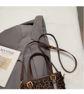 Detail of leopard print bucket bag with brown leather strap and gold buckle on a blazer