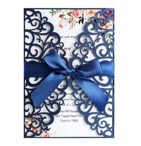 Detail of laser-cut navy blue wedding invitation with ribbon and floral insert card