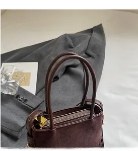 Détail du sac à main en daim marron rouge avec fermeture dorée et doubles anses fines
