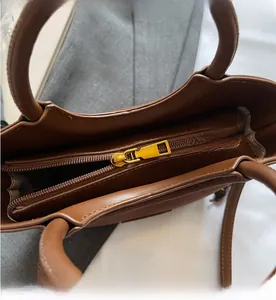 Detail shot of the brown handbag interior showing smooth zipper and gold hardware