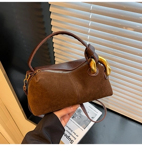 Detail view of deep brown suede handbag with smooth leather trim and gold metal rings