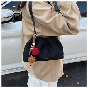 Gros plan du sac seau en daim noir avec cordon de serrage et breloques en peluche