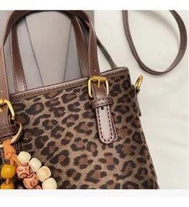 Detail of leopard print handbag showing gold hardware, beaded charm and leather texture
