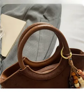 Detailed texture of brown suede and smooth leather handbag with circular handle and wooden beads