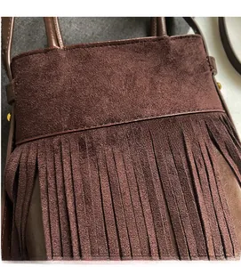 Détail d'un sac bandoulière en daim marron foncé avec de longues franges et clous en métal