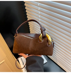 Close-up of vintage brown suede crossbody bag with gold metal rings and leather detail