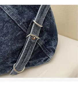 Detailed close-up of blue denim tote bag with silver metal rings and adjustable buckle