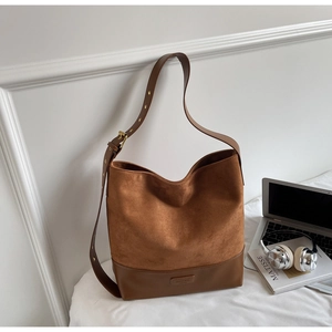 Detail of vintage brown suede tote bag with leather patchwork and adjustable strap