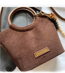 Detail of brown suede bucket bag featuring round wooden handles and colorful bead charms
