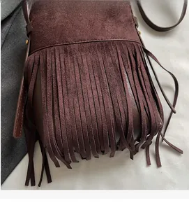 Gros plan sur un sac bandoulière marron foncé avec de longues franges bohèmes