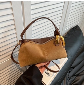 Detail view of vintage brown suede stitching and large gold metal buckle on a shoulder bag