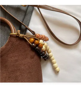 Close-up of brown suede bucket bag with wooden bead tassel and bronze hardware
