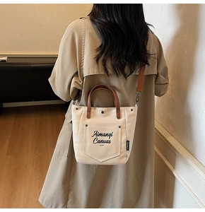 Casual cream canvas tote bag with brown straps shown on shoulder in a lifestyle setting