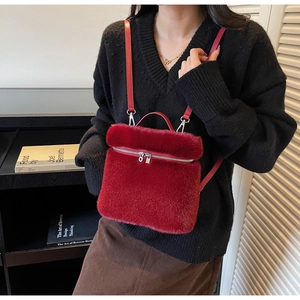 Detail of red plush faux fur backpack showing smooth silver zipper and leather straps