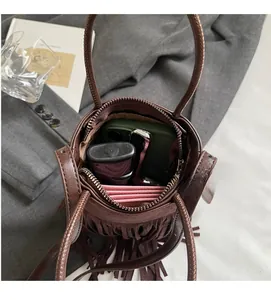 Vue intérieure montrant la capacité du sac seau marron à franges et ses accessoires