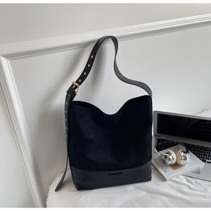 Detail of black suede tote bag showing leather bottom and embossed brand logo mark