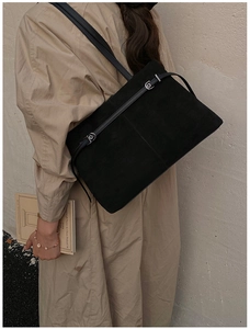 Détail d'un grand sac cabas en daim noir avec bandoulière et boucle sur un mannequin femme