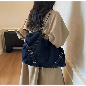 Detail of blue denim tote bag featuring white contrast stitching and silver metal hardware